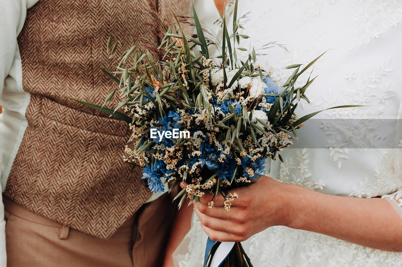 Midsection of couple holding bouquet