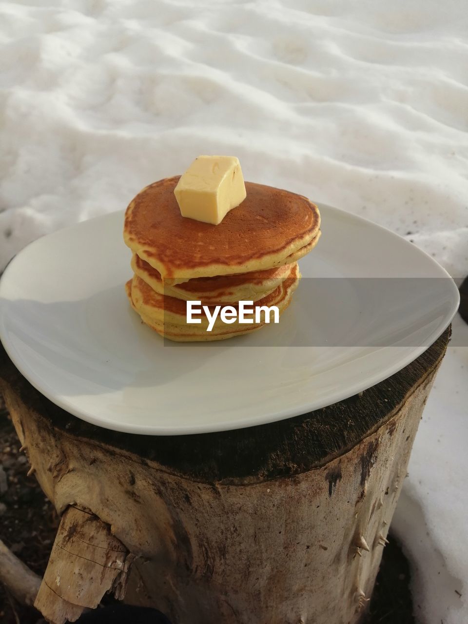 High angle view of pancake in plate on tree stump