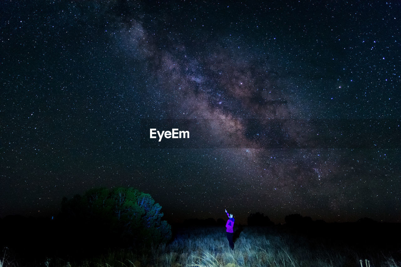 Woman standing on field against star field