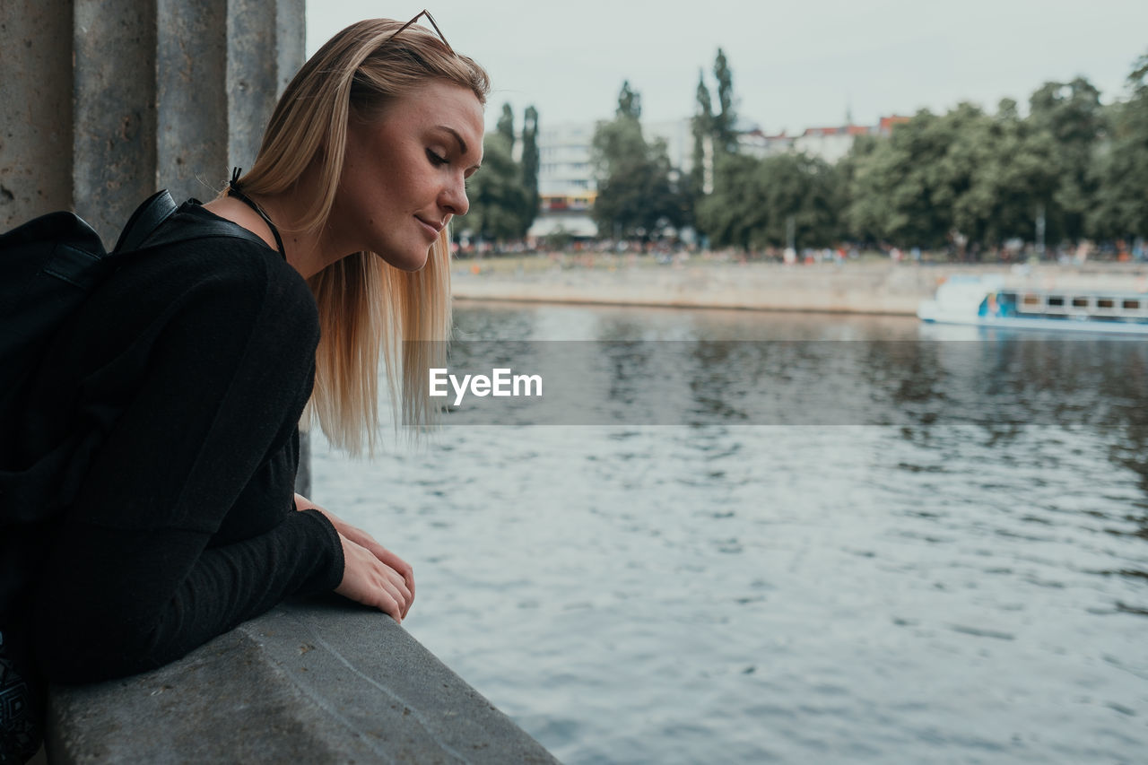 WOMAN SITTING BY LAKE