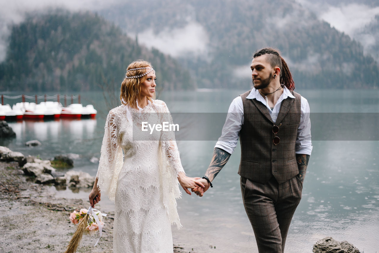 A happy couple in love and married embrace in nature by the lake and the misty mountains