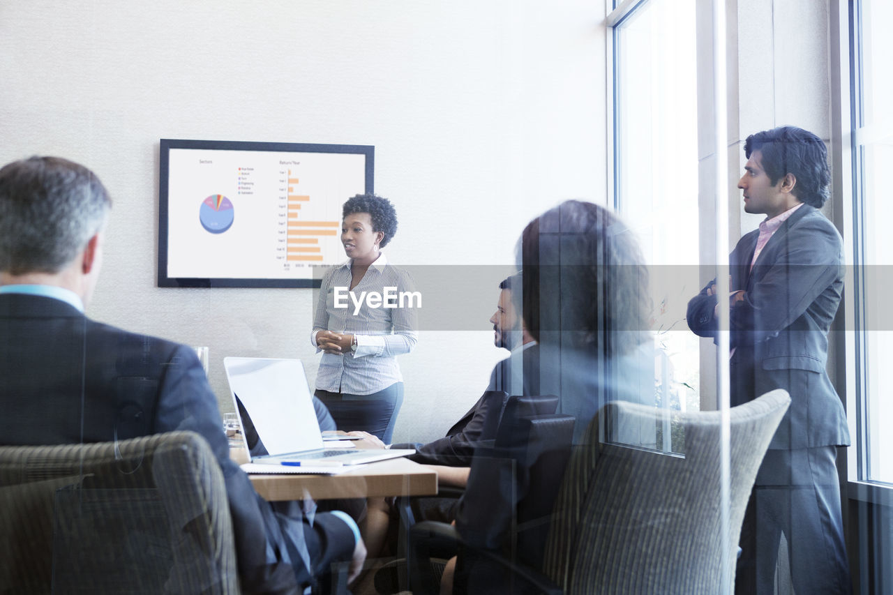 Businesswoman giving presentation to colleagues in conference room