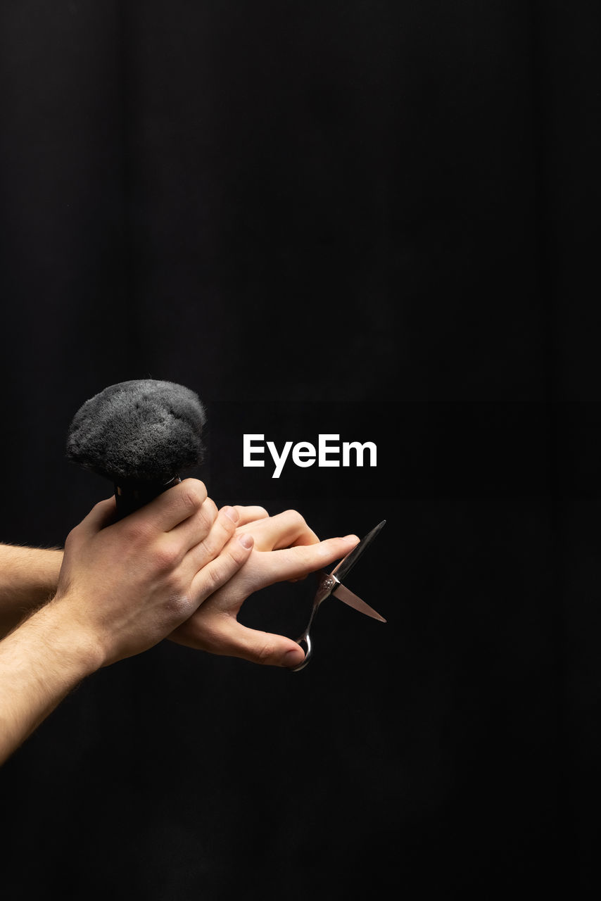 Cropped hand of woman gesturing against black background