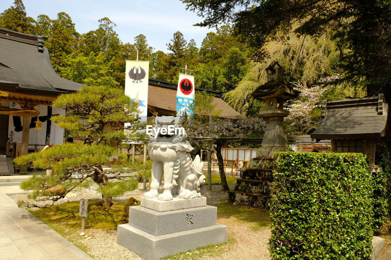 STATUE AMIDST TREES AND BUILDINGS