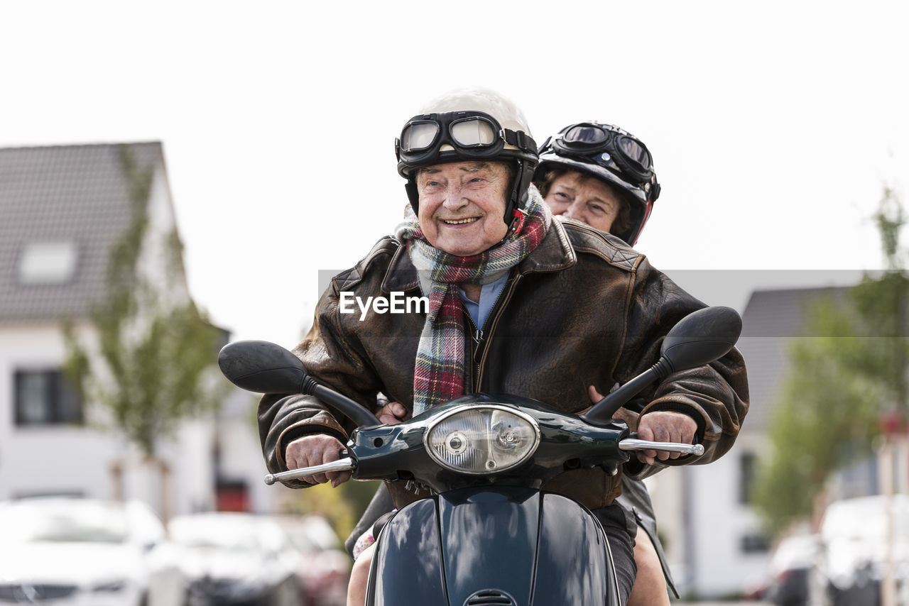 Happy senior couple riding motor scooter