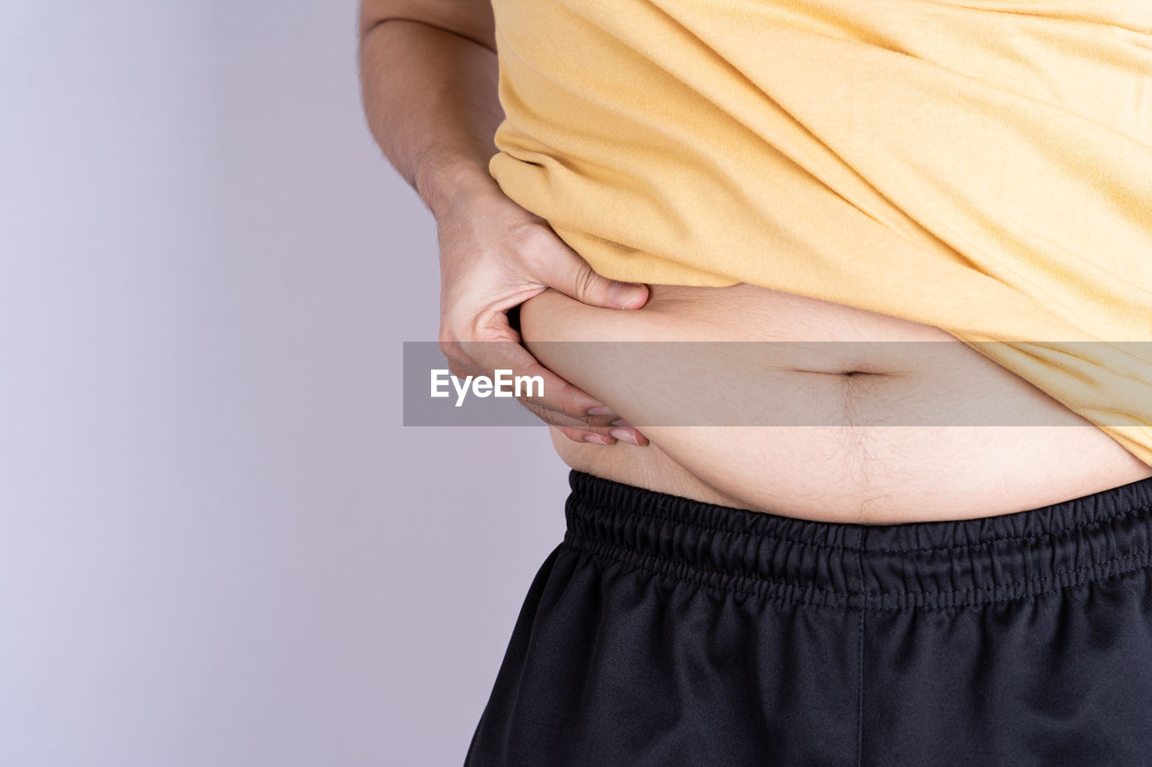 LOW SECTION OF WOMAN AGAINST WHITE BACKGROUND