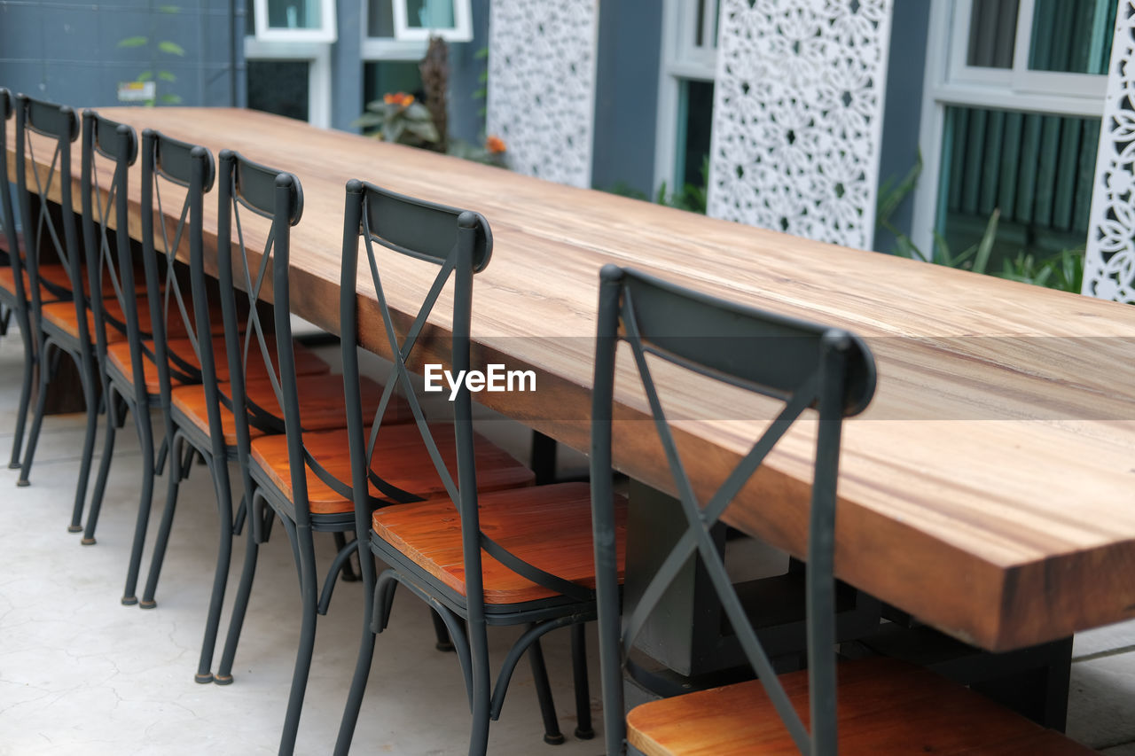 EMPTY CHAIRS AND TABLE IN RESTAURANT AGAINST BUILDING