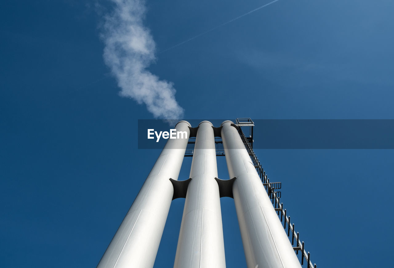 Low angle view of chimneys against blue sky