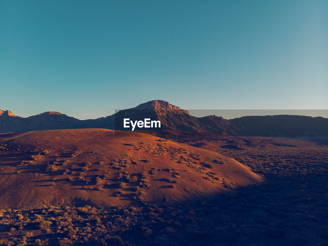 Scenic view of desert against clear blue sky