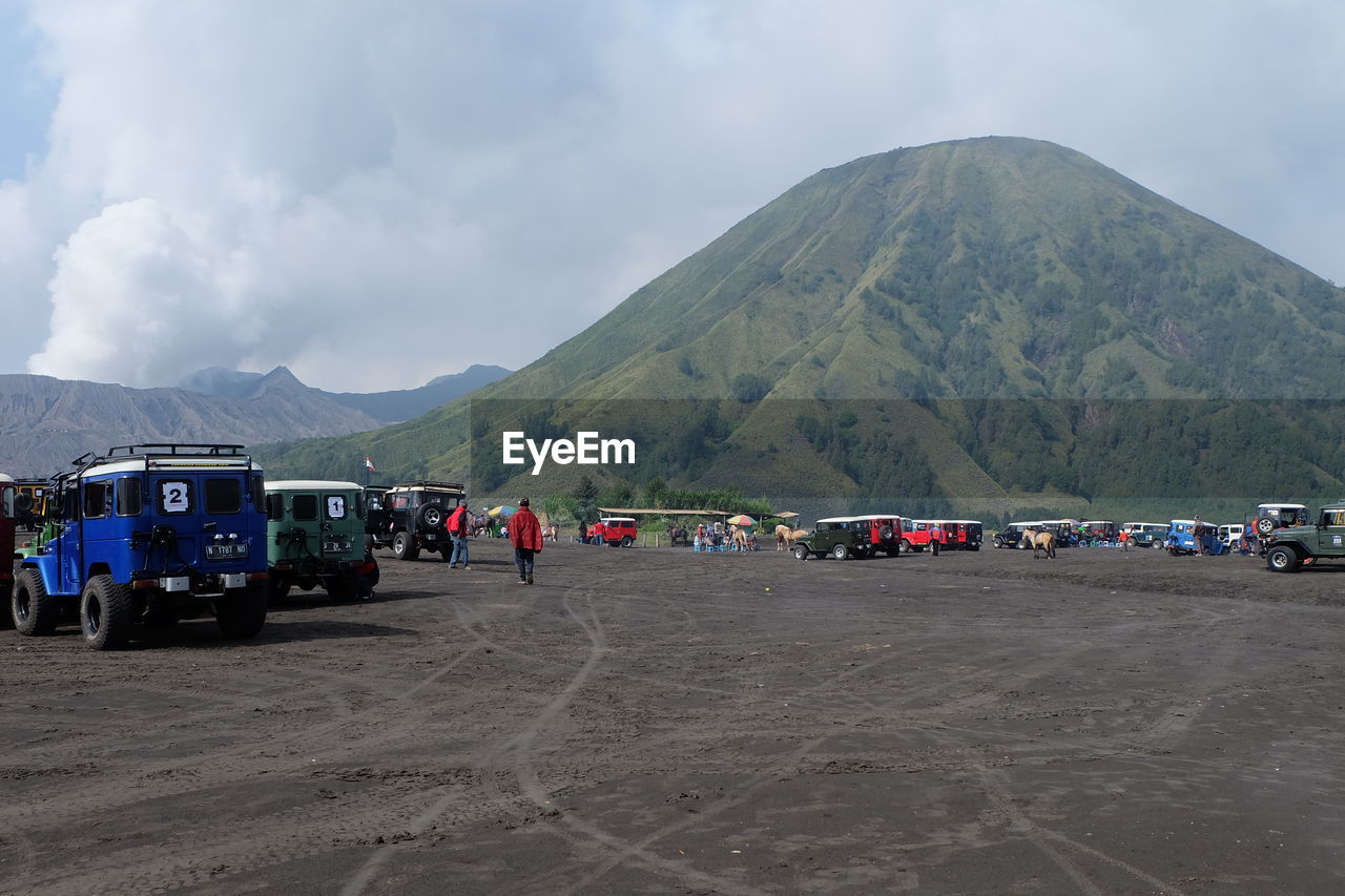 Vehicles on ground against mountains