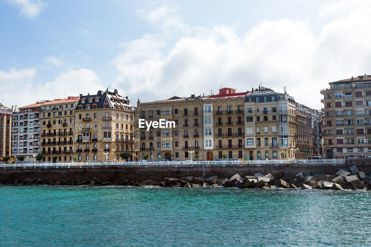 Buildings by sea against sky