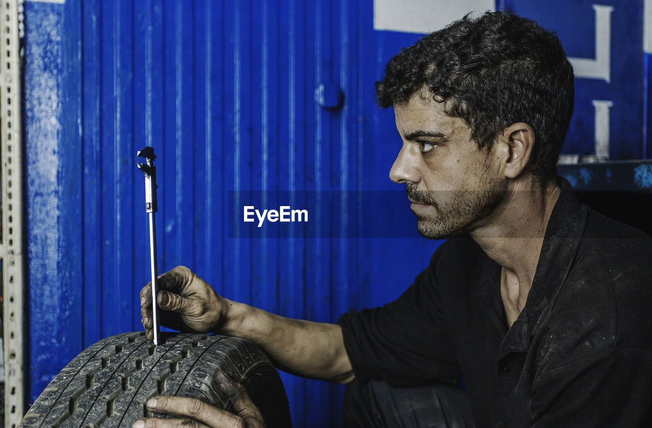 Side view mechanic using caliper while checking, measuring car tire tread in professional workshop