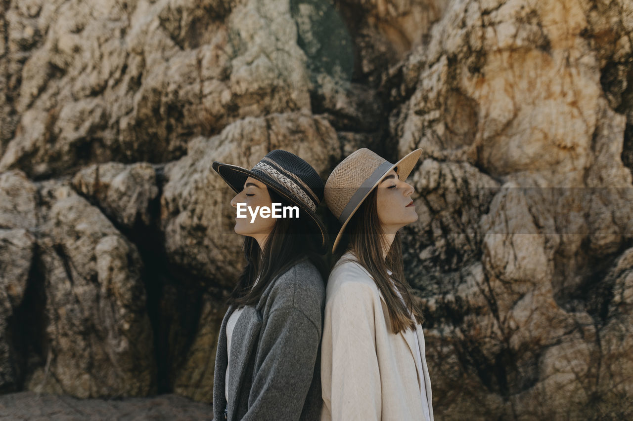 Young sisters back to back by rock formation