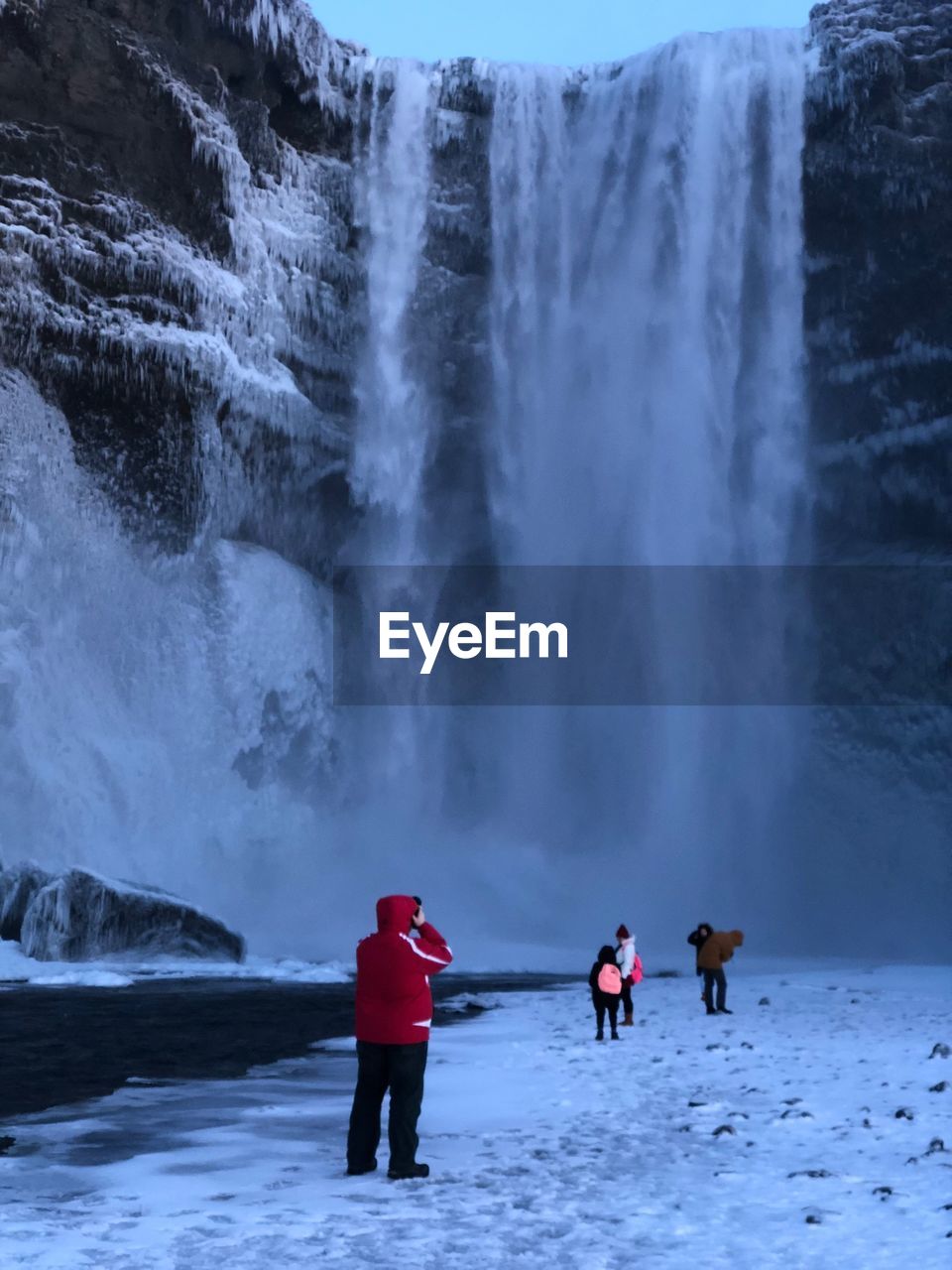 Man photographing waterfall during winter