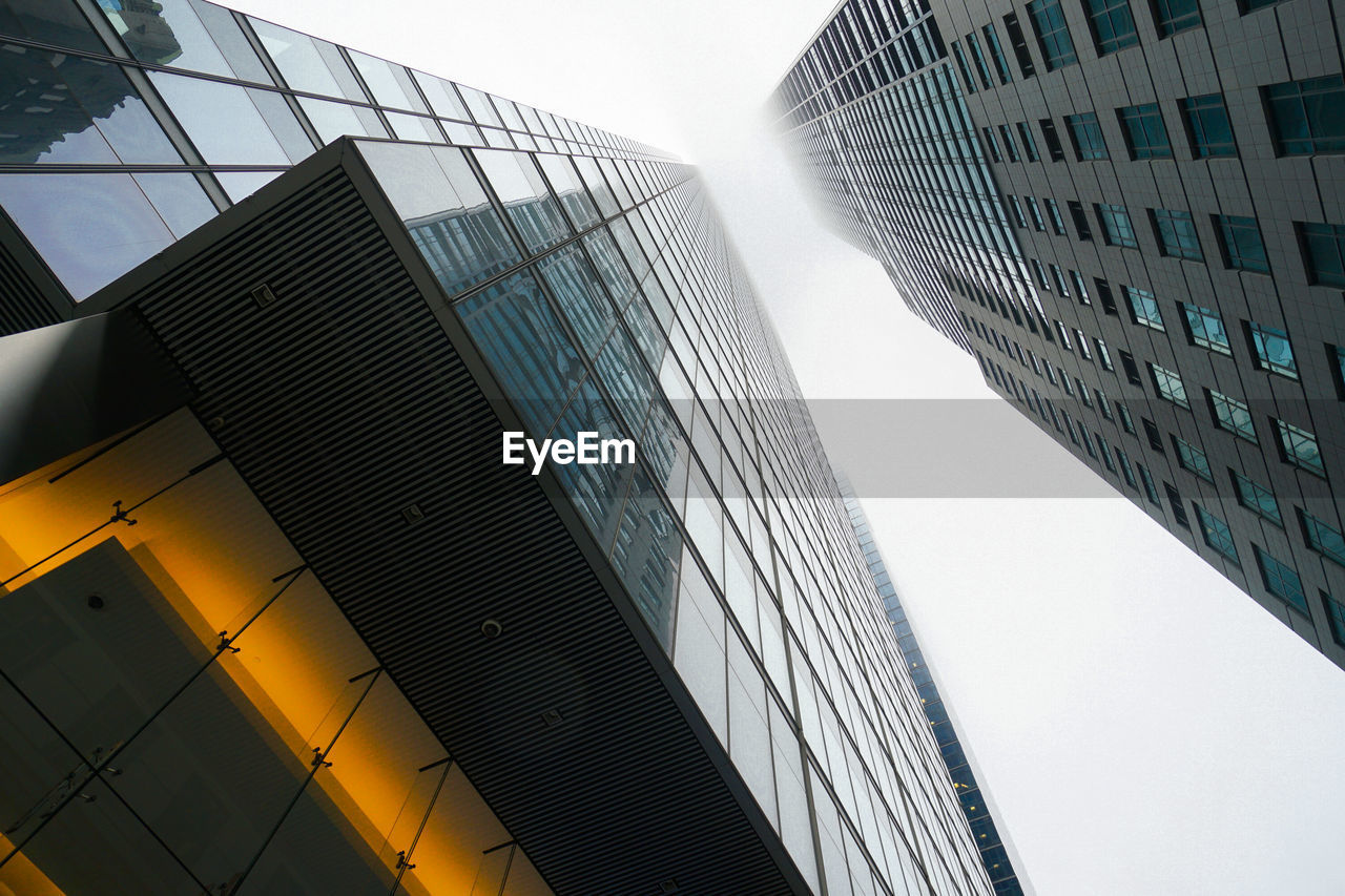 Directly below shot of modern buildings against clear sky