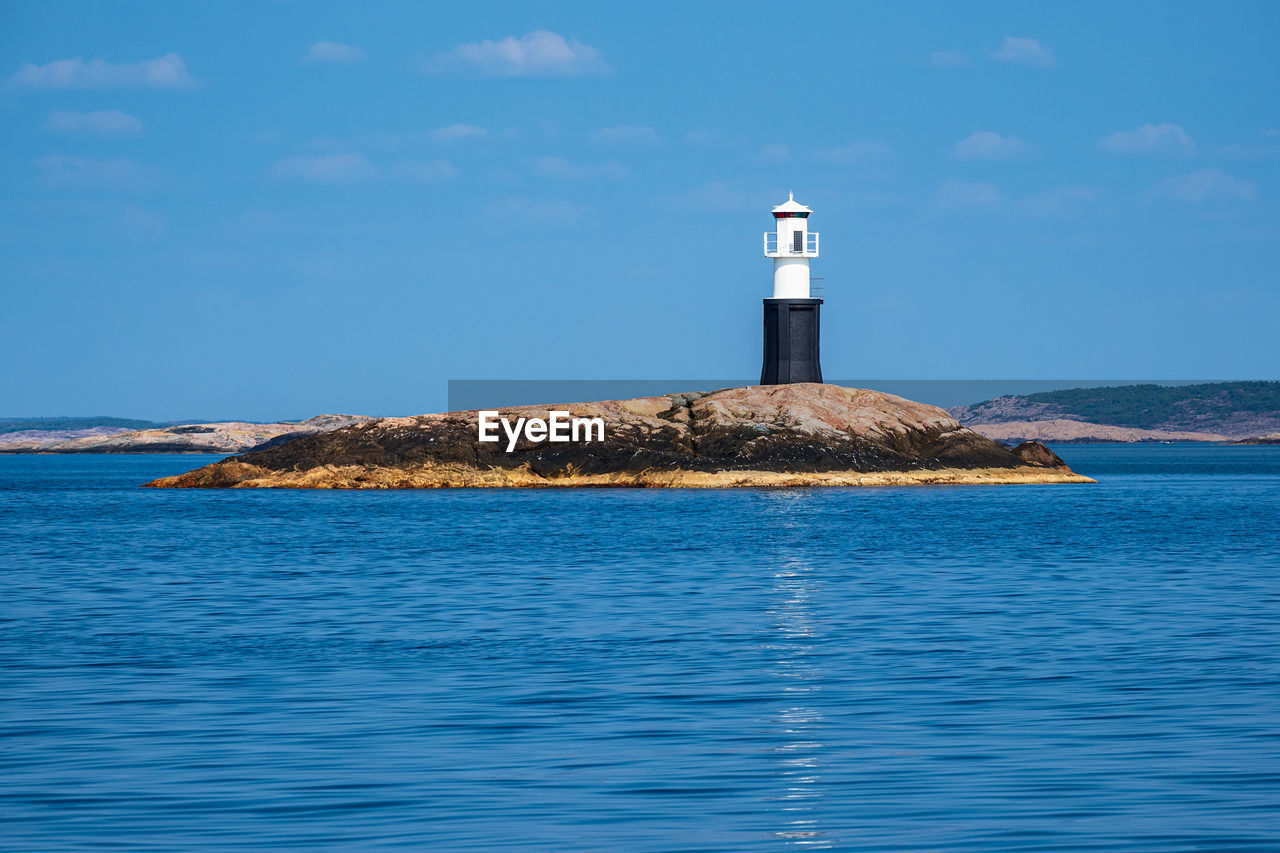 LIGHTHOUSE BY SEA AGAINST BUILDING