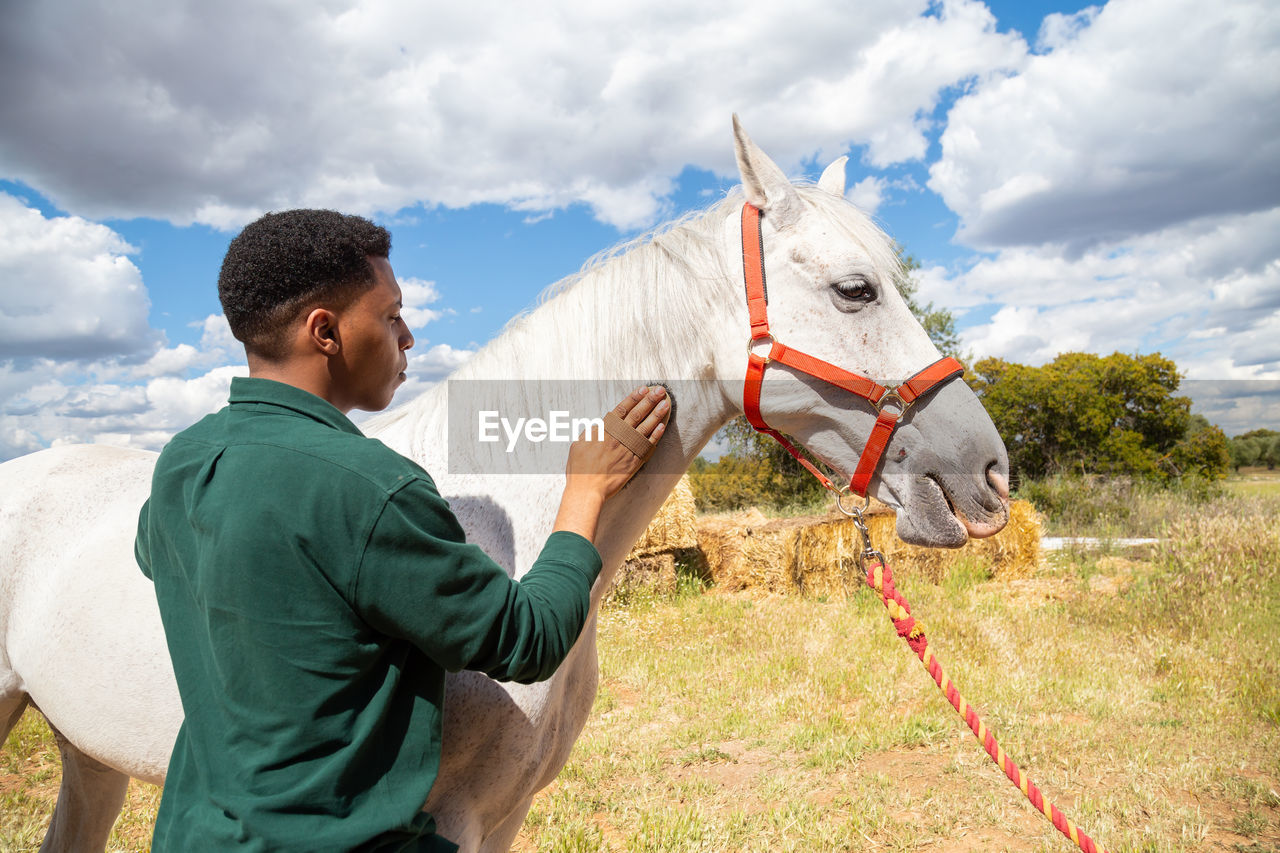 SIDE VIEW OF SENIOR MAN HOLDING UMBRELLA AGAINST SKY