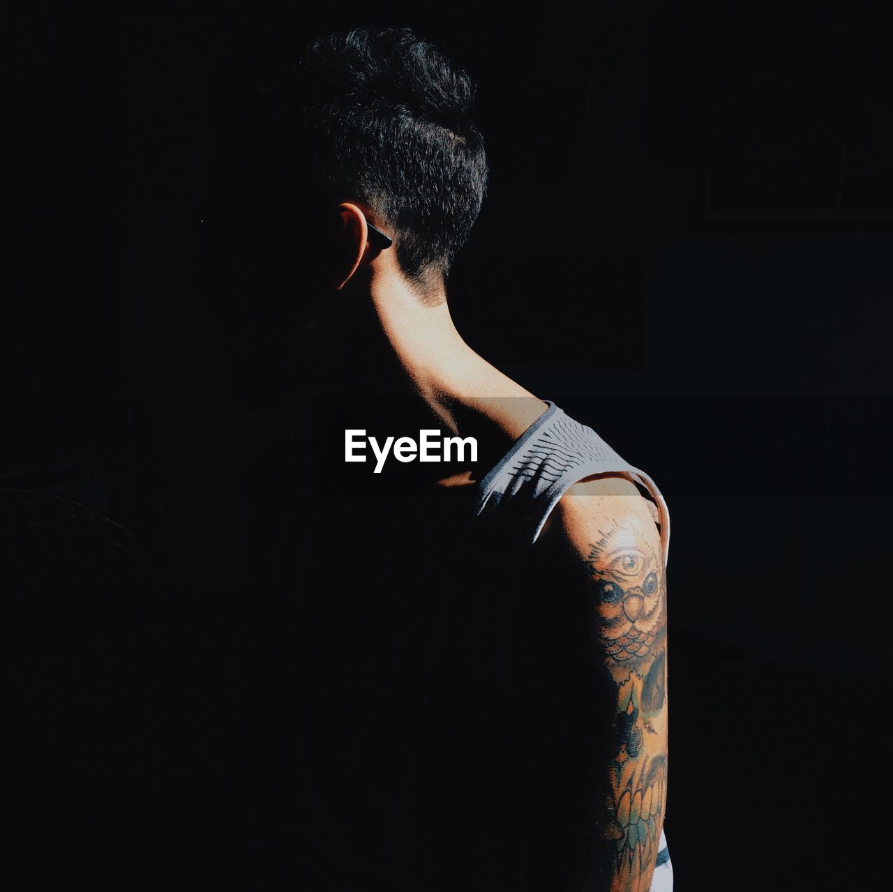 Man with tattoo against black background