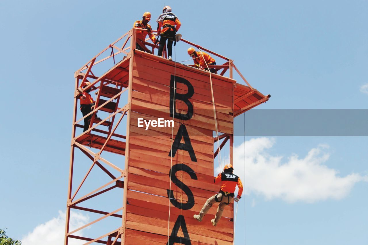 LOW ANGLE VIEW OF PEOPLE STANDING AT CONSTRUCTION SITE