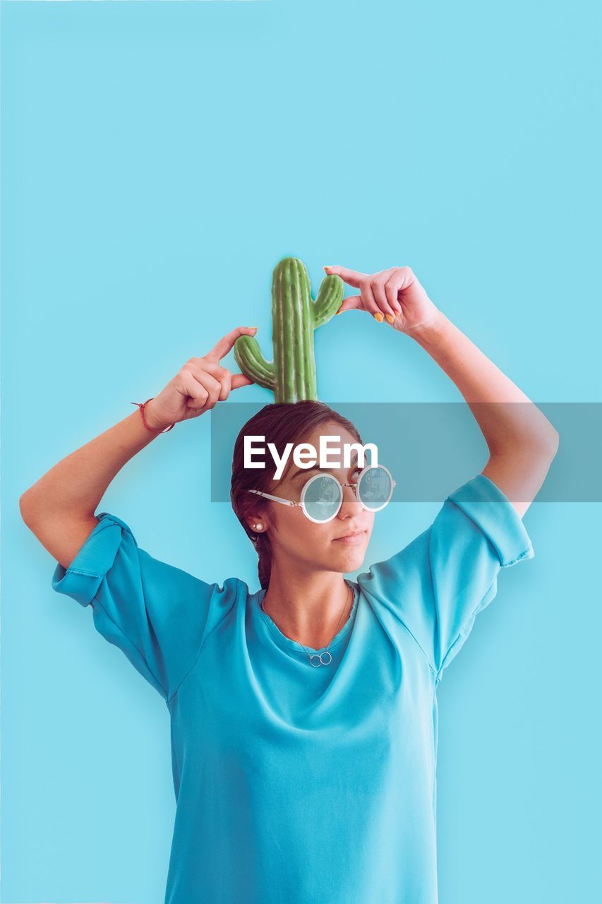 Young woman with cactus against blue background