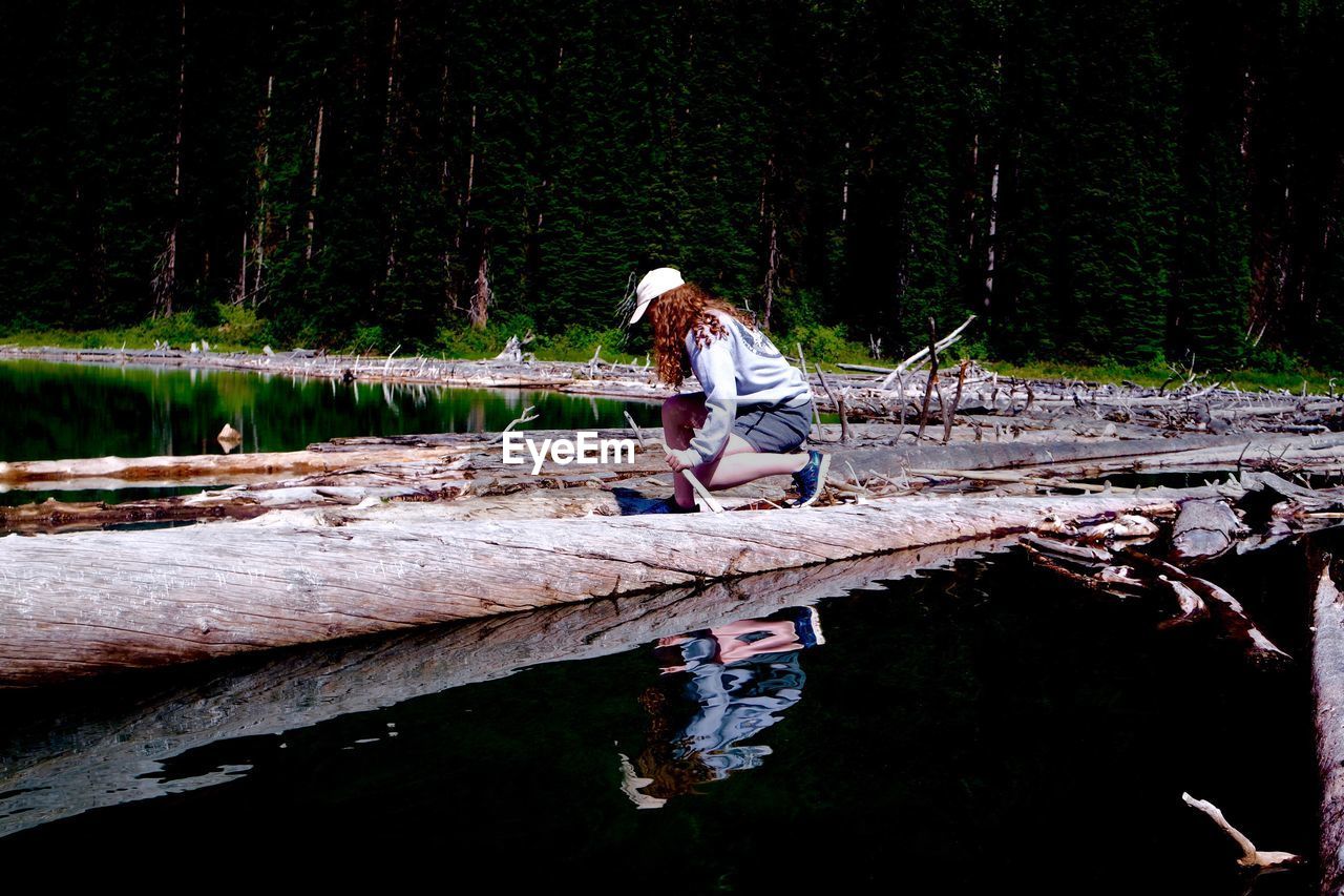 Woman sitting by tree in forest