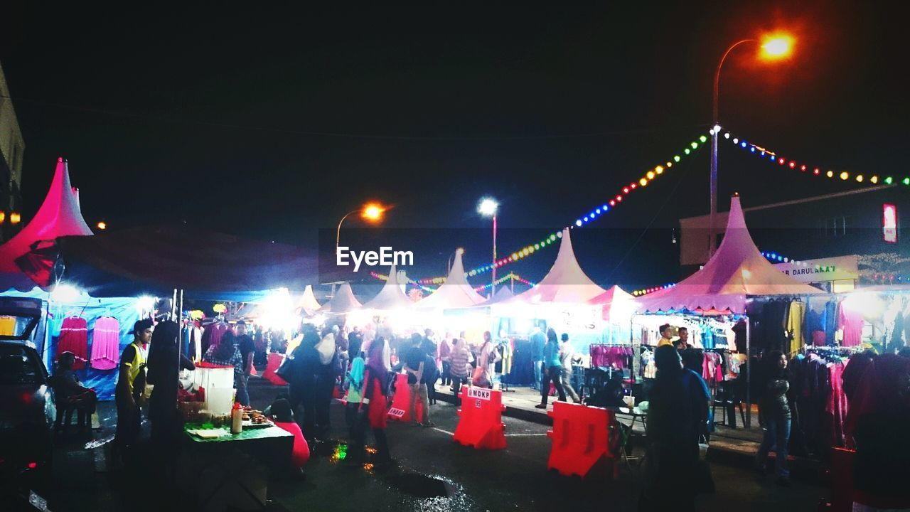 People walking on illuminated street market at night