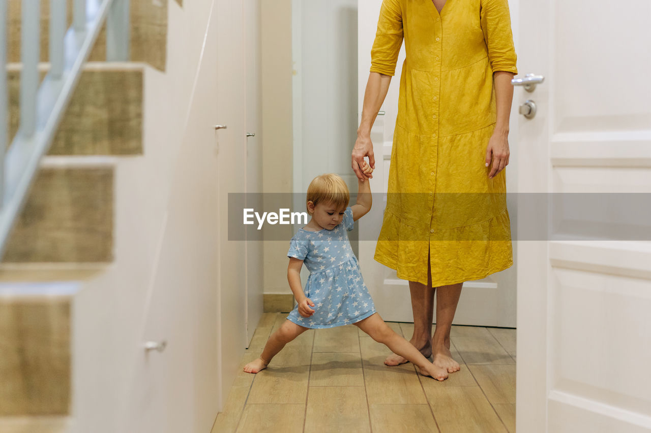 Little playful daughter has fun at home holding her mother's hand.