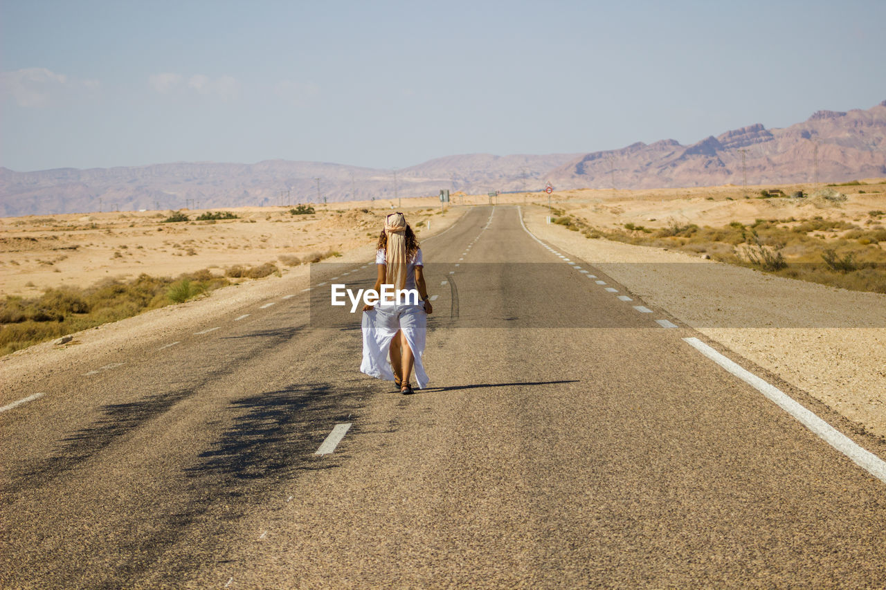 Woman walking on road in desert