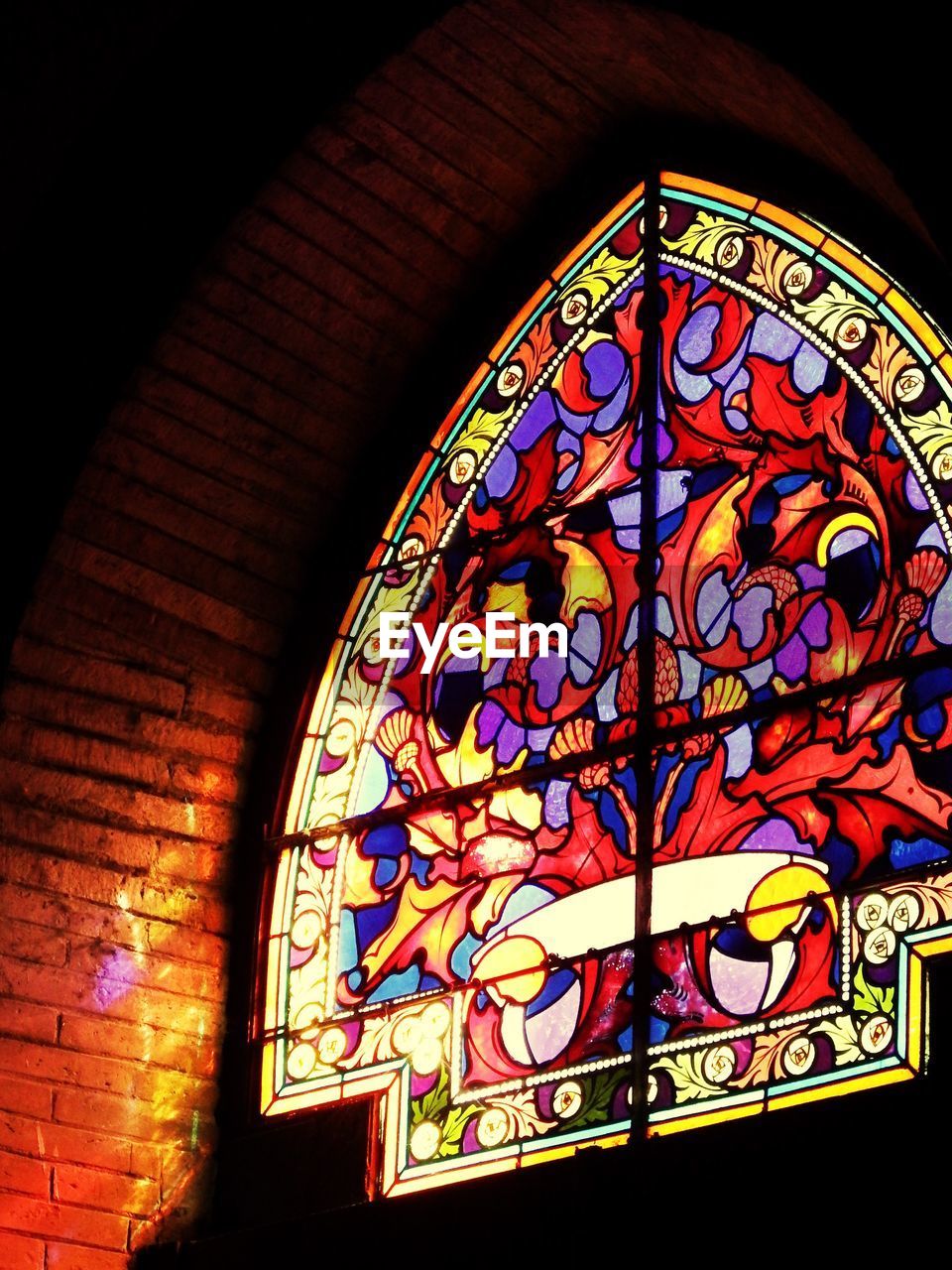 LOW ANGLE VIEW OF STAINED GLASS WINDOW IN CHURCH