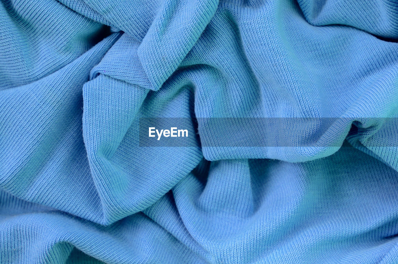 FULL FRAME SHOT OF BLUE FABRIC AGAINST COLORED BACKGROUND