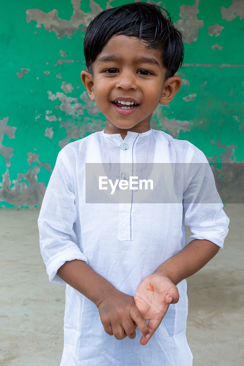 PORTRAIT OF A SMILING BOY STANDING OUTDOORS