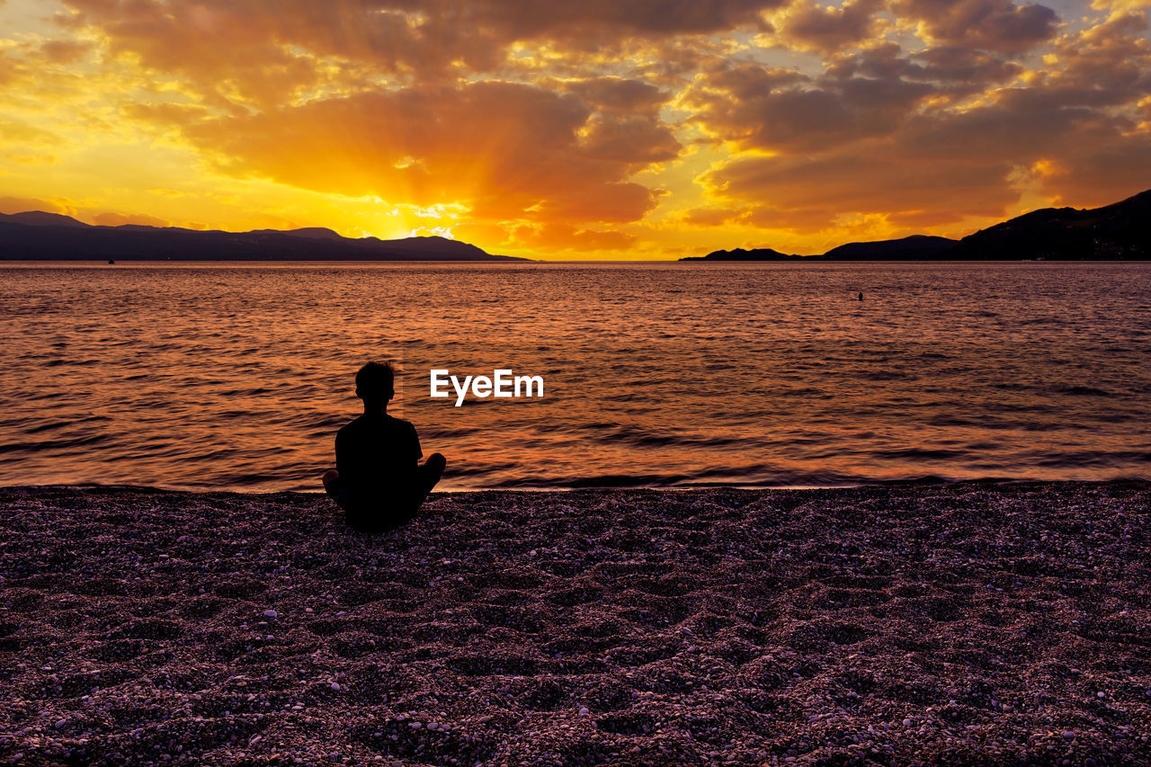 SILHOUETTE MAN LOOKING AT SEA AGAINST SUNSET SKY