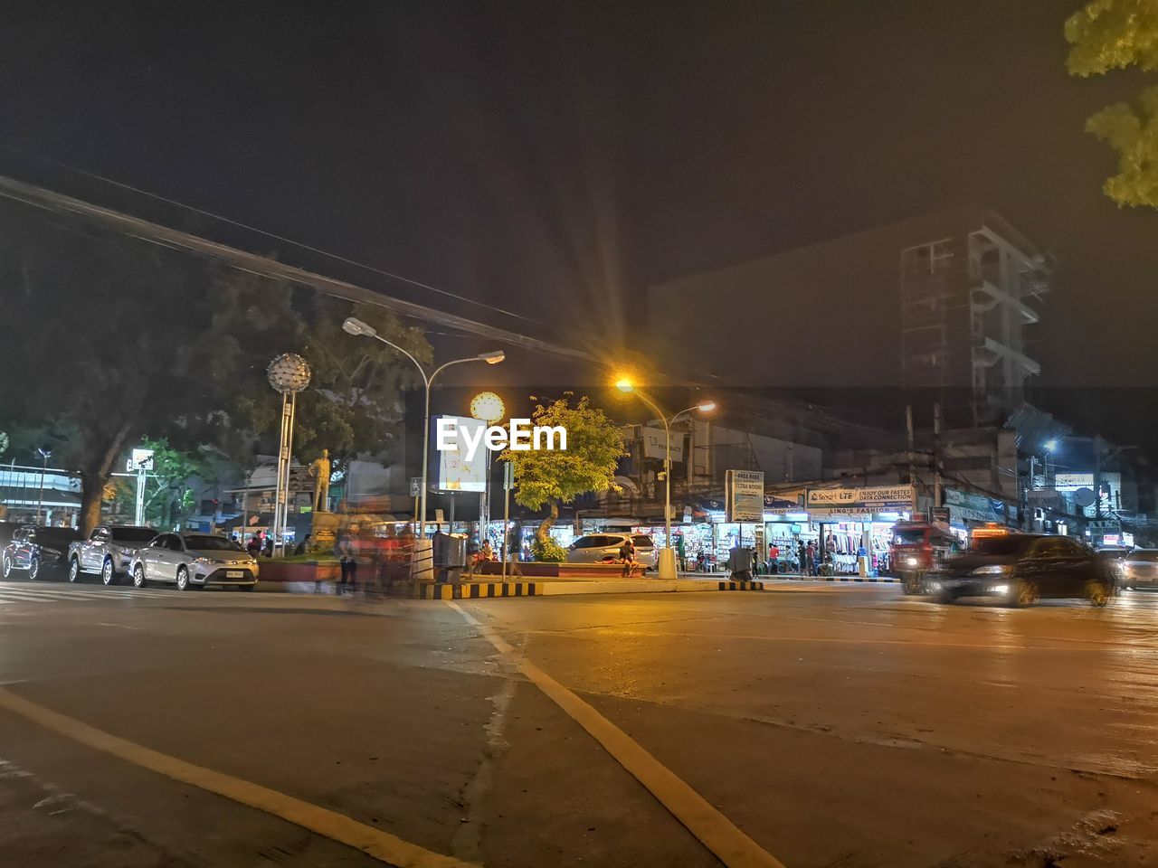 City street by illuminated buildings at night