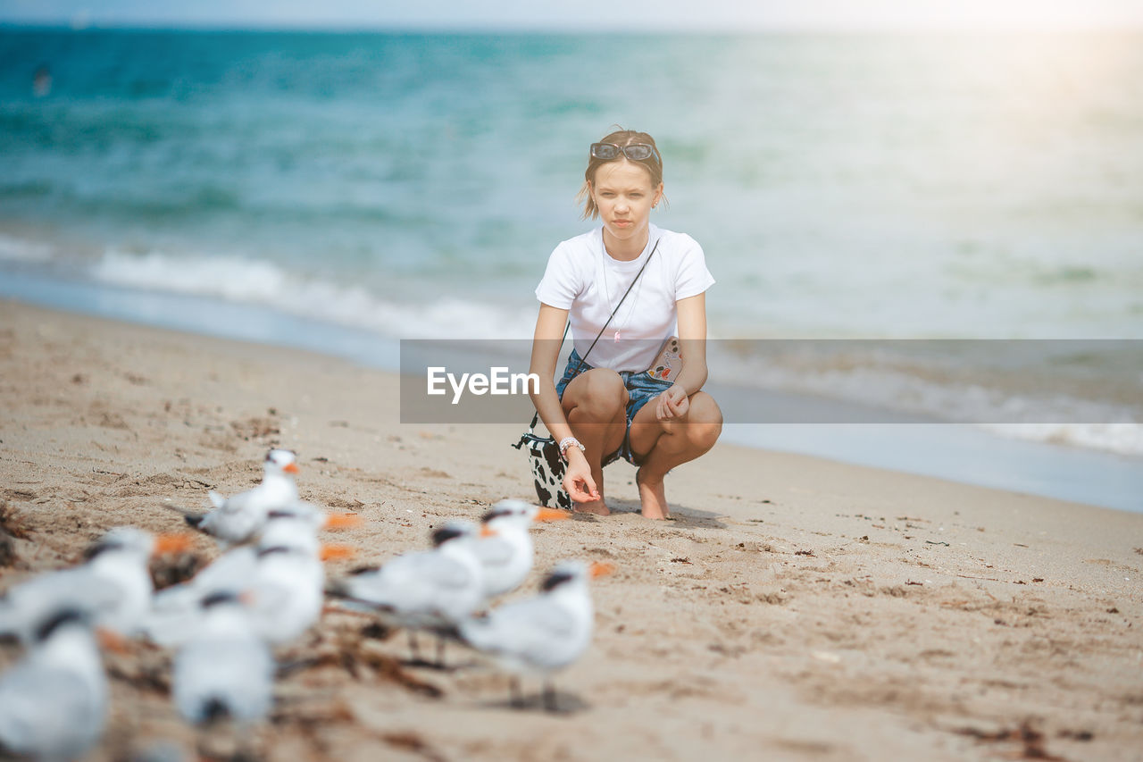 portrait of young woman sitting on sand at beach