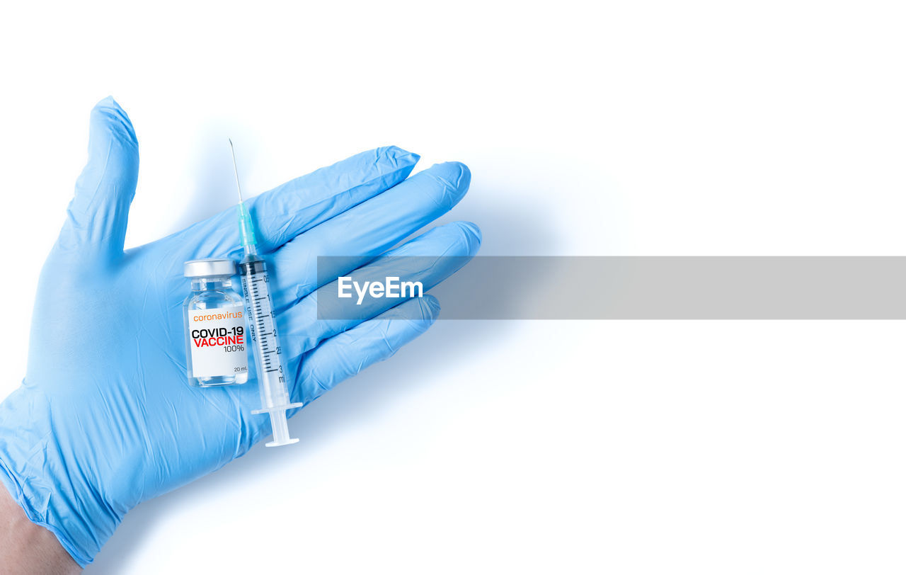 Doctor or scientist hand in blue nitrile gloves holding flu, measles, coronavirus vaccine 