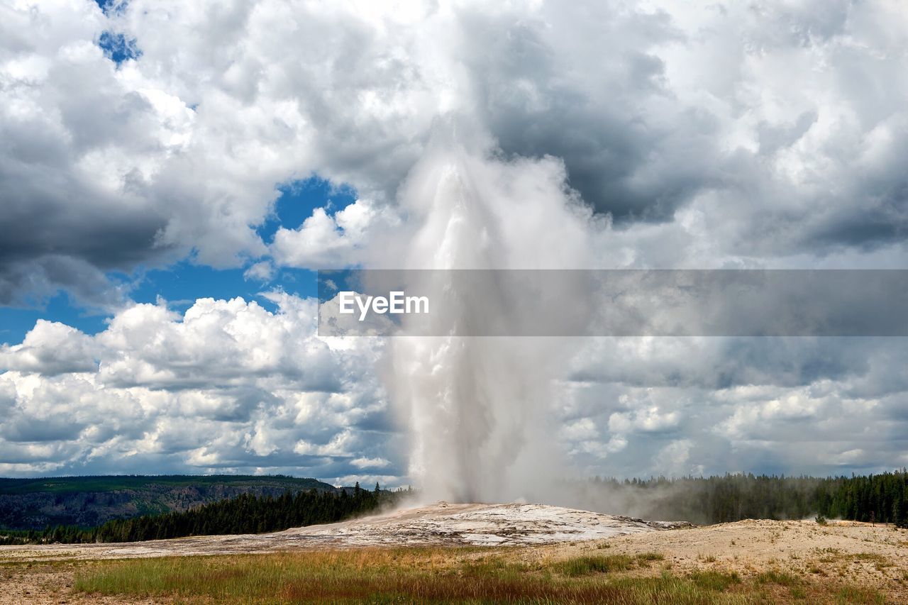 Geyser spraying against cloudy sky