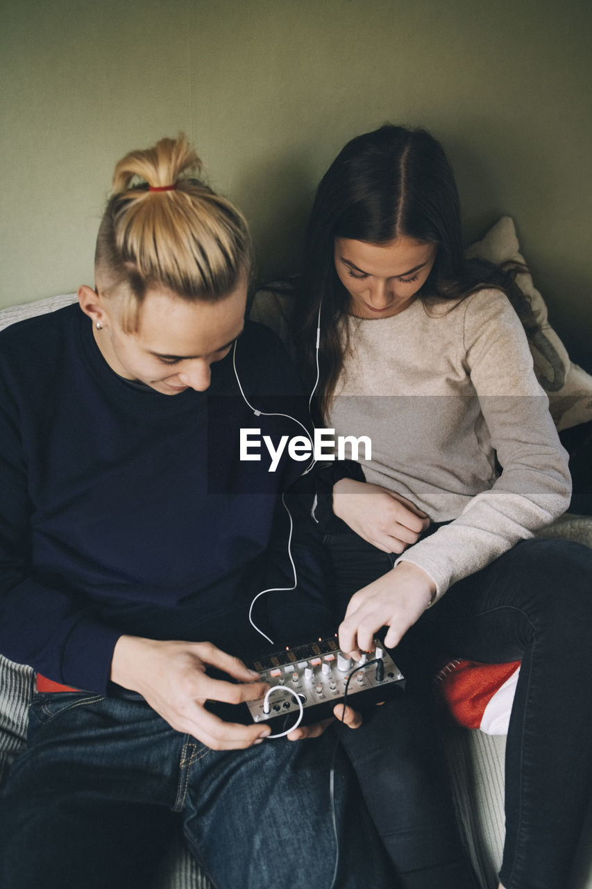 High angle view of male and female friends using sound mixer at bedroom