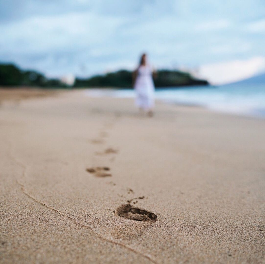 Woman walking at beach against cloudy sky