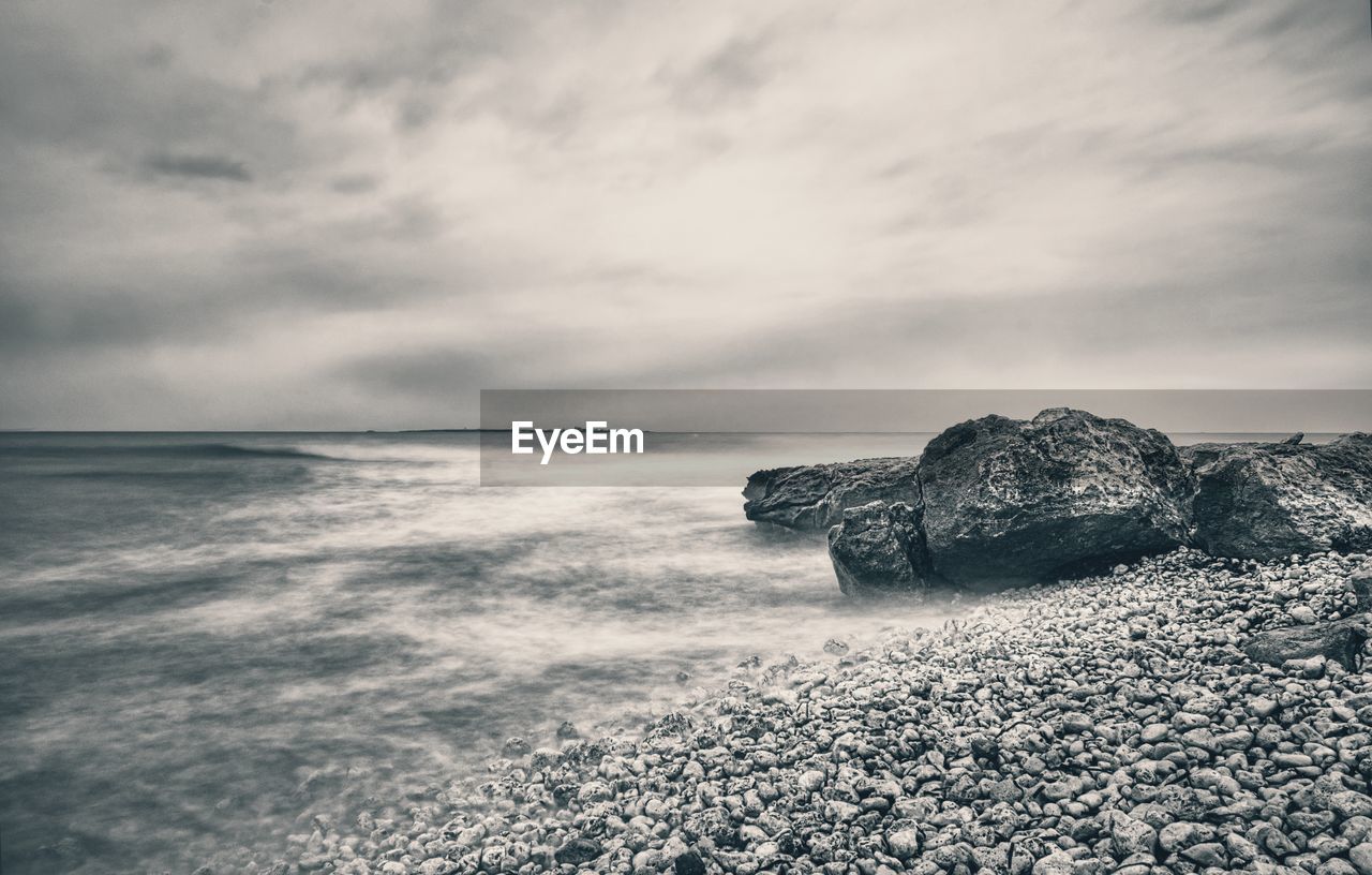 Scenic view of rocks on beach against sky