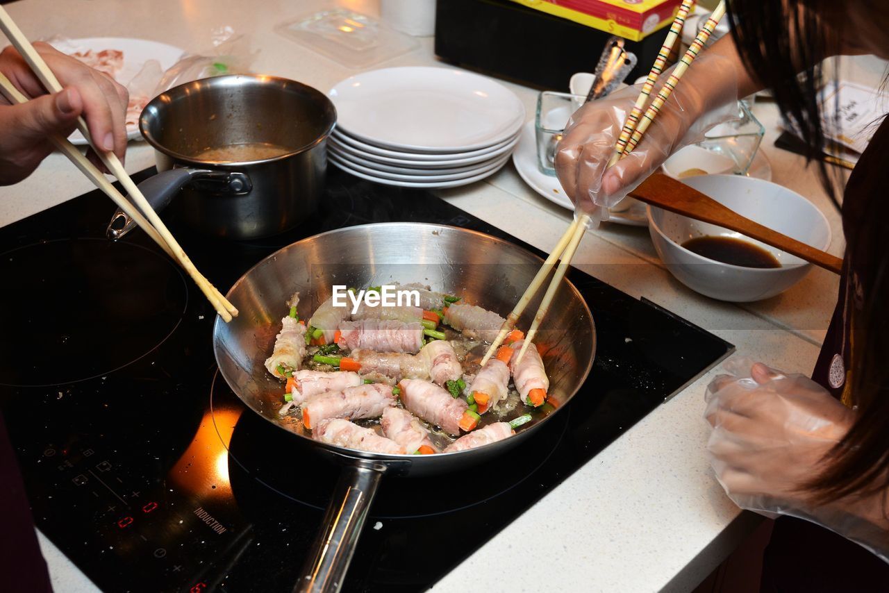 Cropped image of hands taking food from frying pan