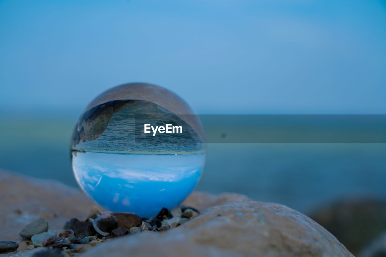 Blue water on rock in sea against sky