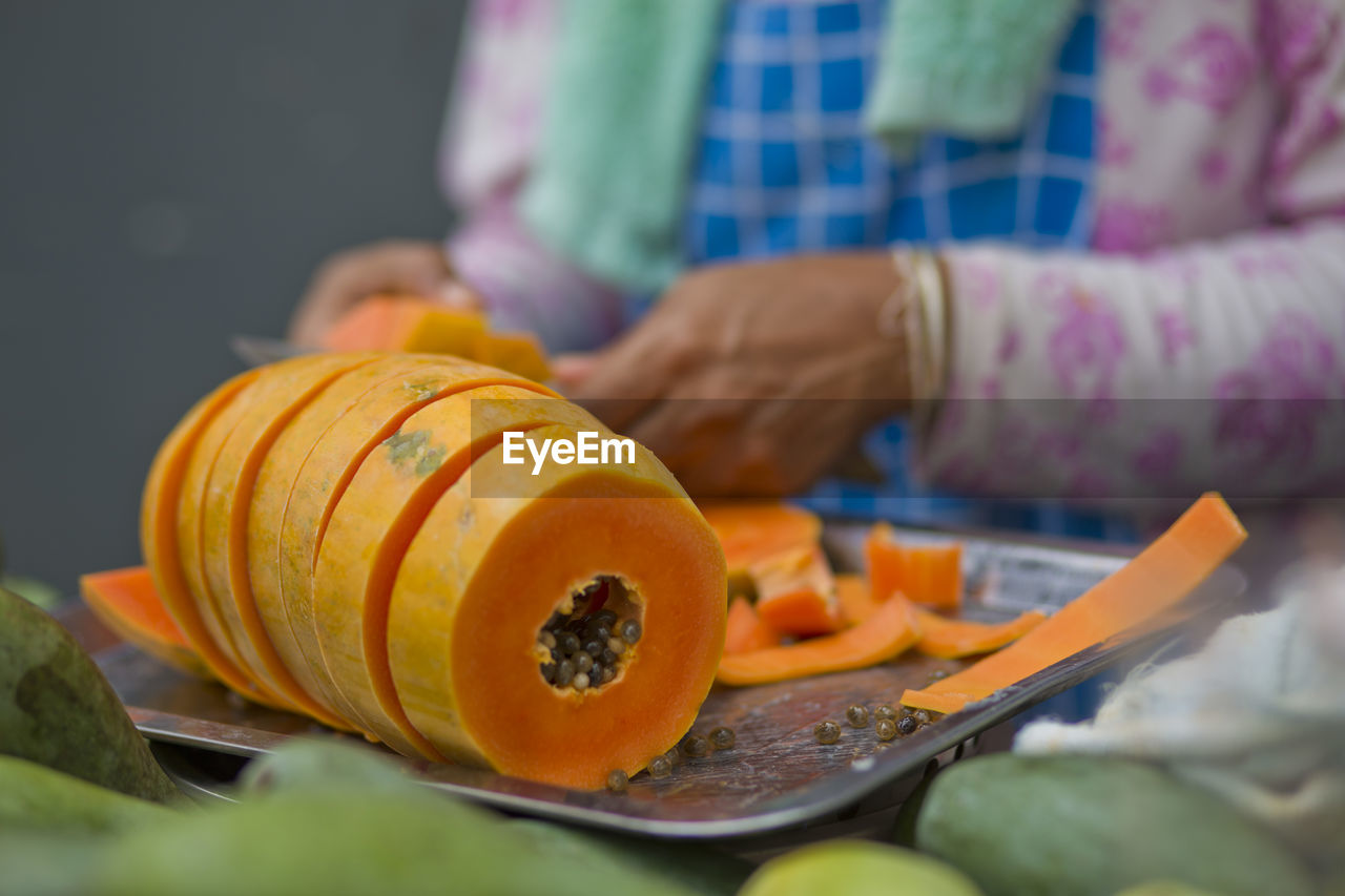 Midsection of woman cutting papaya on tray