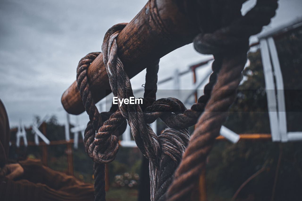 CLOSE-UP OF ROPE TIED TO RUSTY METAL CHAIN