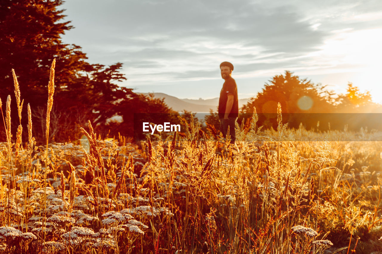 Man standing on field against sky at sunset