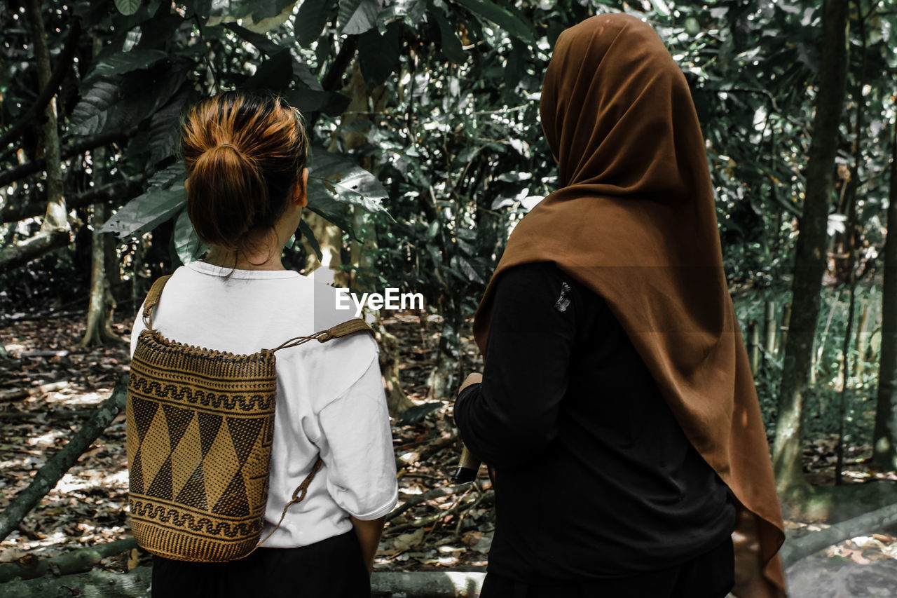 Rear view of couple standing against trees