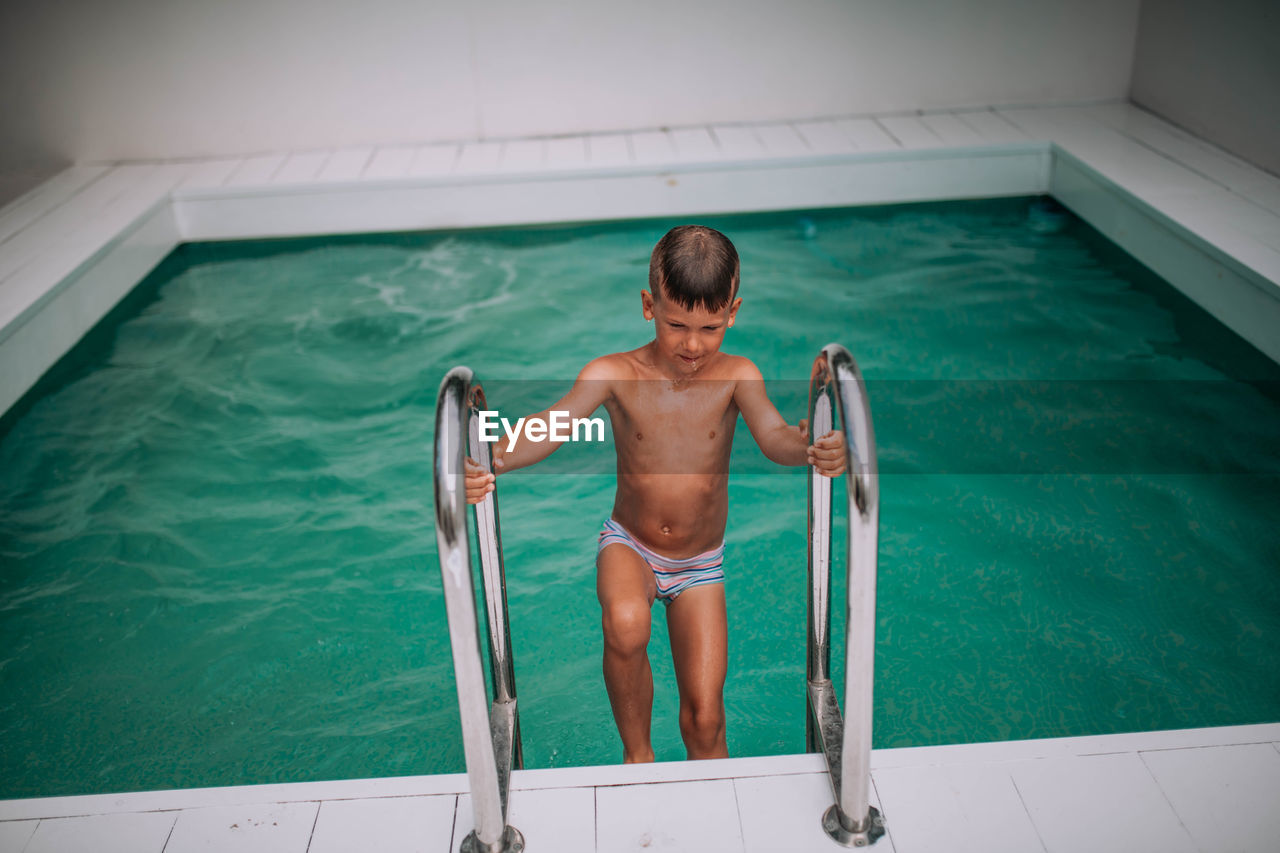 HIGH ANGLE VIEW OF BOY IN SWIMMING POOL