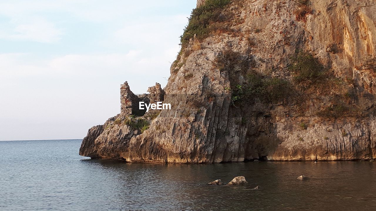 Rock formations by sea against sky