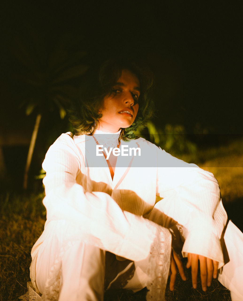 Young woman looking away while sitting on land