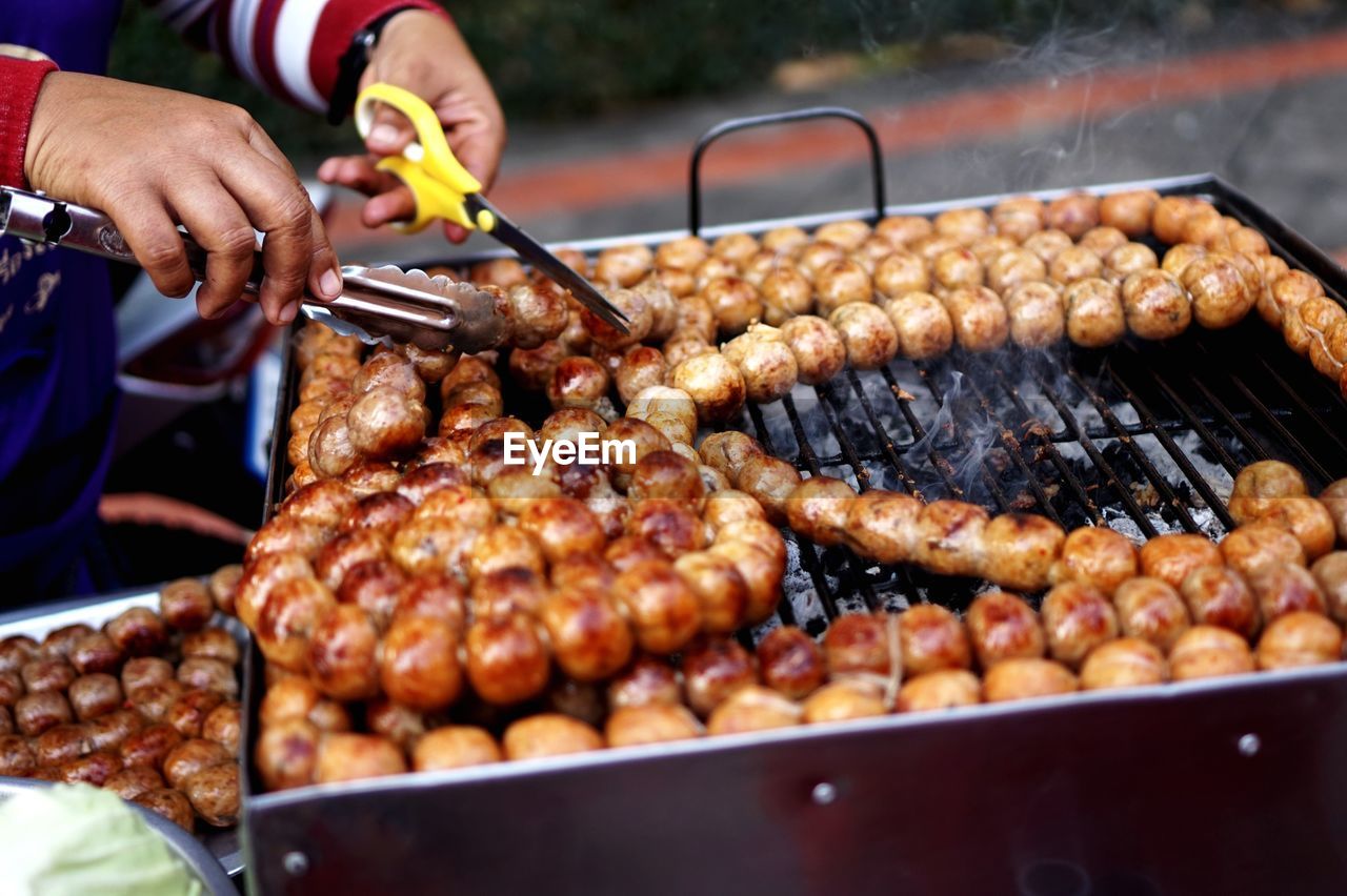 Cropped hand preparing food on barbecue grill