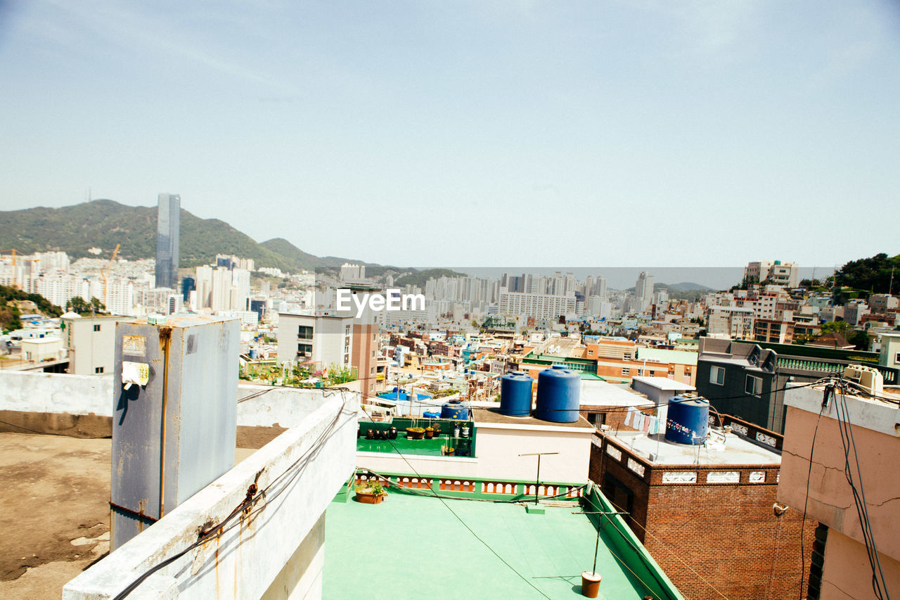 HIGH ANGLE VIEW OF CITYSCAPE BY SEA AGAINST SKY